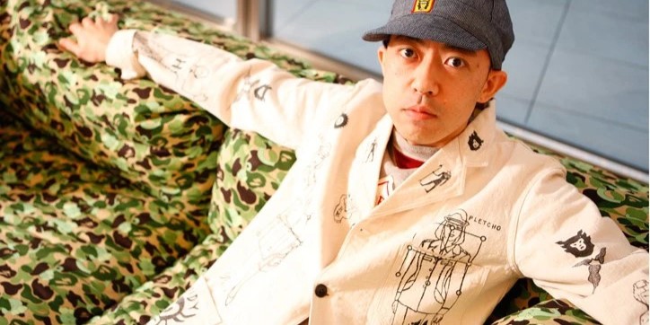 Nigo sitting on a couch covered in Bape camo design