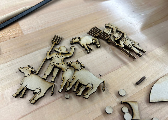 A pile of the automata's farmer and cow characters after being laser cut.